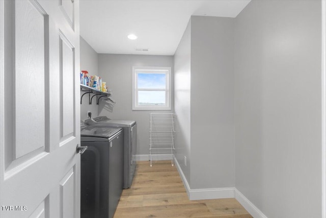 laundry room with washer and dryer and light wood-type flooring