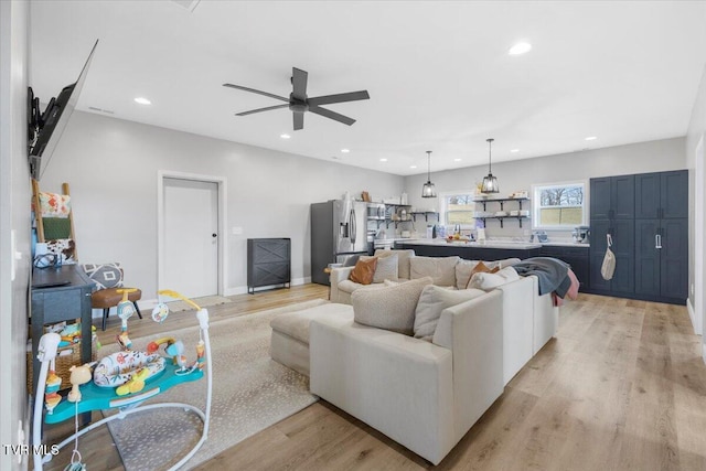 living room with ceiling fan and light hardwood / wood-style flooring