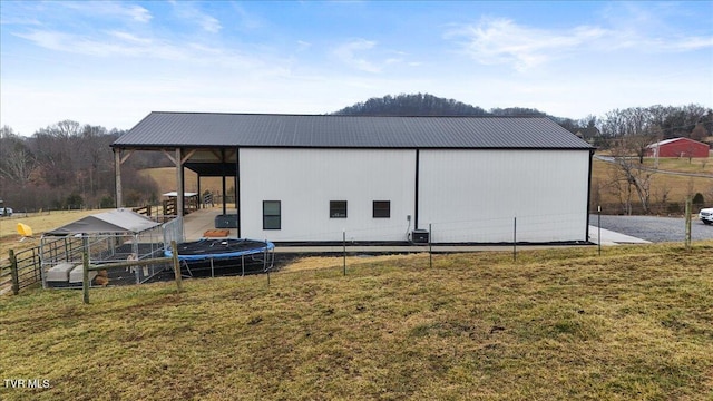 view of outdoor structure with cooling unit, a yard, and a trampoline