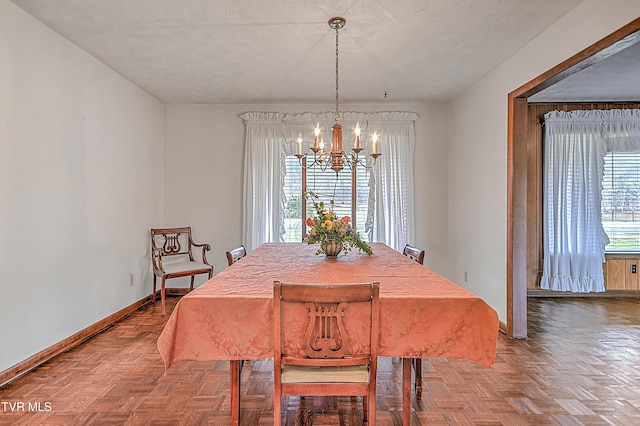 dining room with parquet floors, a notable chandelier, and a textured ceiling