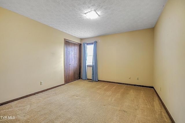 unfurnished room with light colored carpet and a textured ceiling