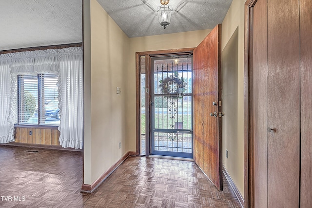 entryway with dark parquet floors and a textured ceiling