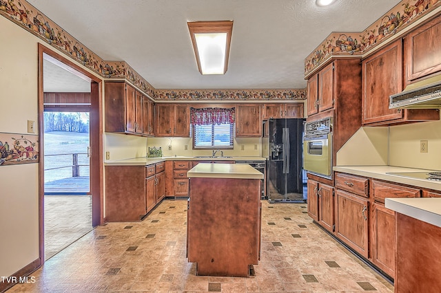 kitchen featuring a center island, sink, a textured ceiling, and black appliances