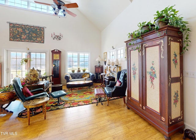 living room with ceiling fan, high vaulted ceiling, and light wood-type flooring