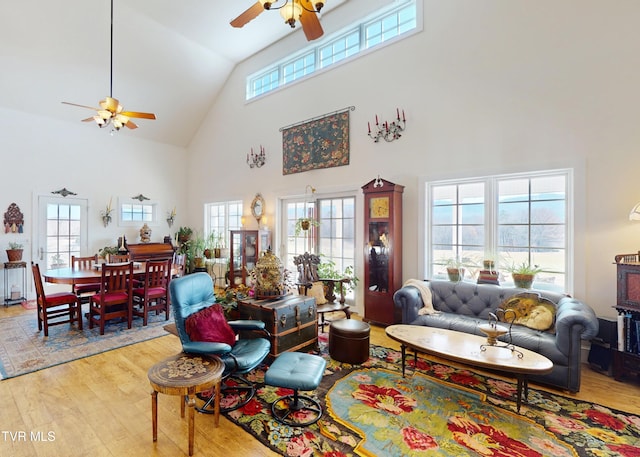 living room with high vaulted ceiling, ceiling fan, and light hardwood / wood-style flooring