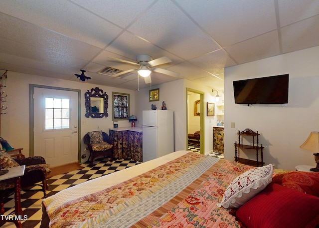 bedroom with connected bathroom, a paneled ceiling, ceiling fan, and white fridge