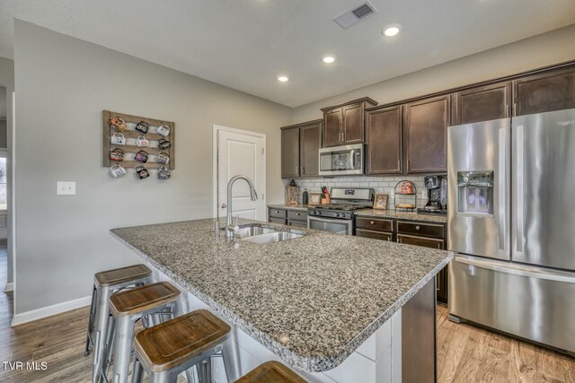 6758 Wildlife Cir, Piney Flats, TN 37686 - kitchen featuring sink, light stone counters, a kitchen breakfast bar, an island with sink, and stainless steel appliances