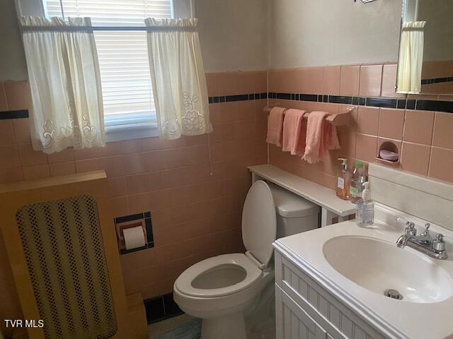 bathroom with vanity, tile walls, and toilet