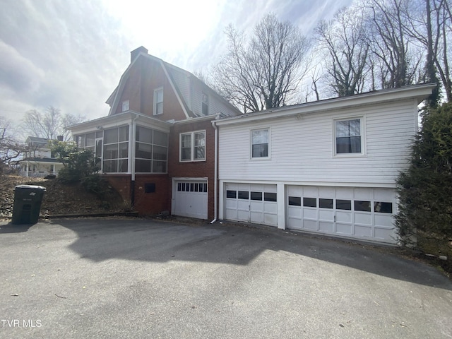 back of house with an attached garage, driveway, and a sunroom