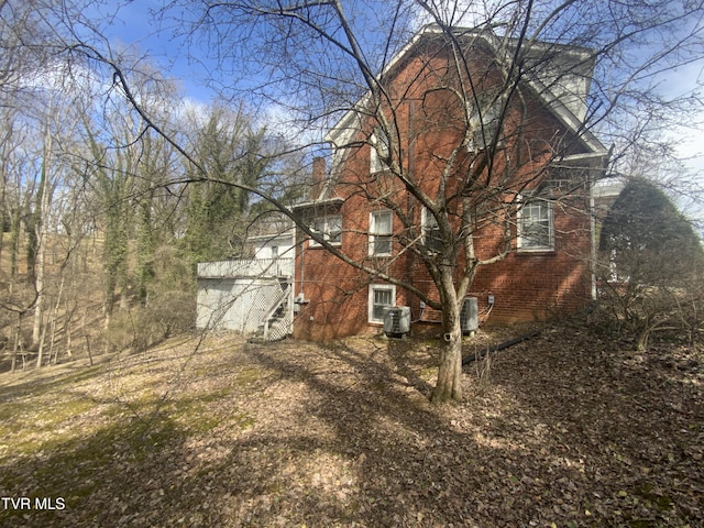 view of side of property featuring stairs, central air condition unit, and a chimney