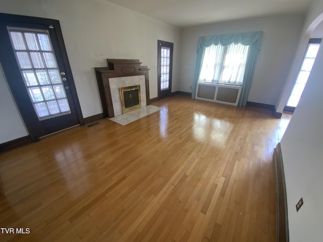 unfurnished living room with radiator, a fireplace, crown molding, and wood-type flooring