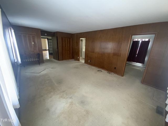 unfurnished living room featuring wood walls