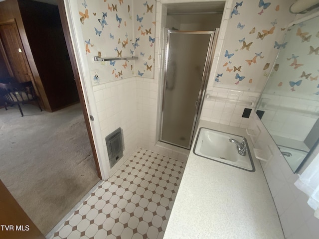 full bath with visible vents, wallpapered walls, a stall shower, tile walls, and a sink