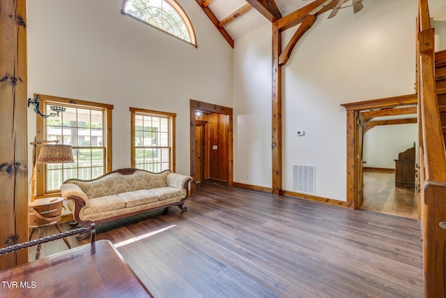 living room featuring hardwood / wood-style floors, beam ceiling, and high vaulted ceiling