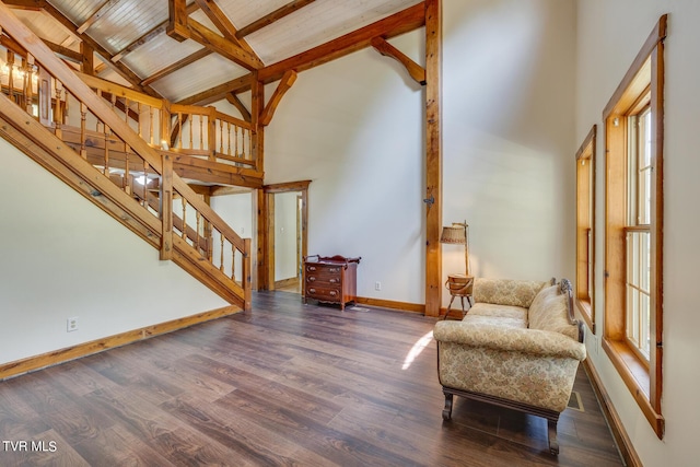 living area with dark hardwood / wood-style flooring, beam ceiling, and high vaulted ceiling