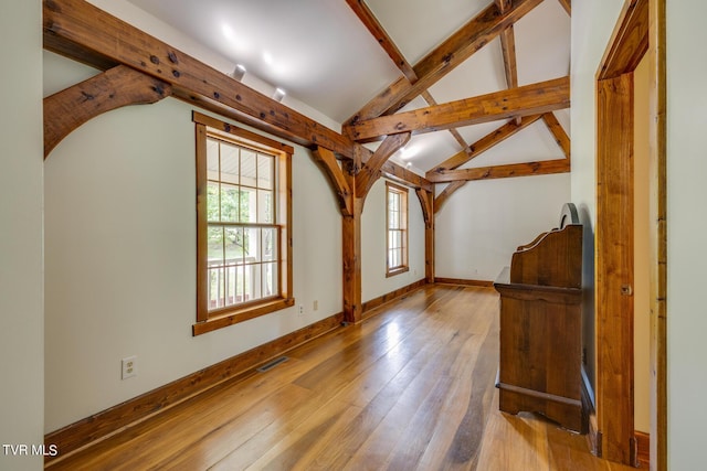 additional living space with vaulted ceiling with beams and light wood-type flooring