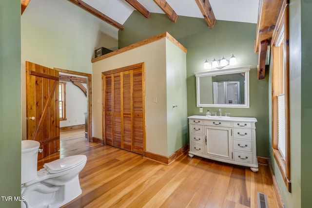 bathroom with high vaulted ceiling, wood-type flooring, vanity, toilet, and beam ceiling