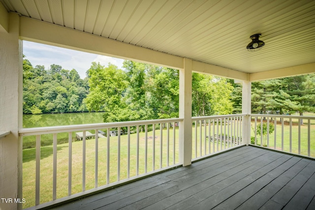 wooden deck with a water view and a lawn