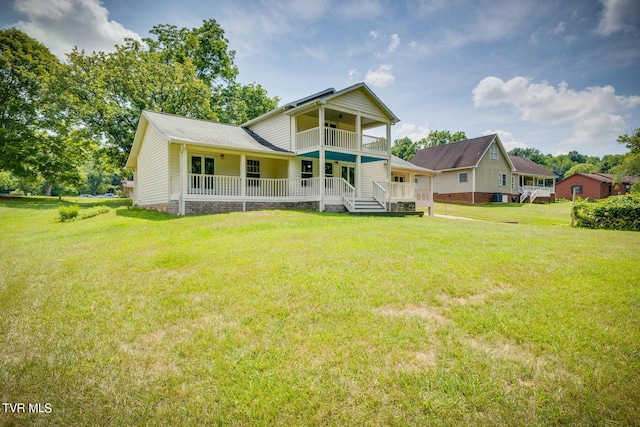 rear view of house featuring a porch, a balcony, and a yard