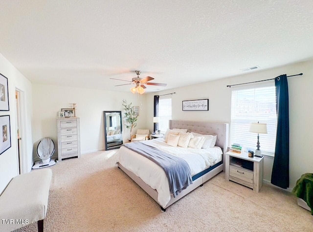 bedroom with ceiling fan, light carpet, and a textured ceiling