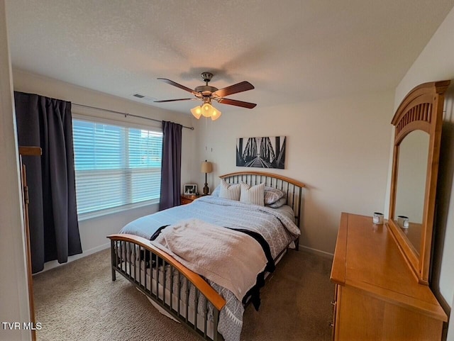 bedroom with ceiling fan, dark carpet, and a textured ceiling