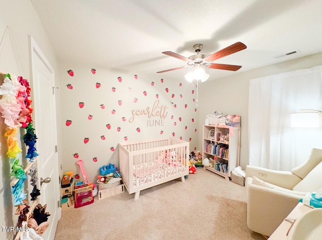 carpeted bedroom with a nursery area and ceiling fan