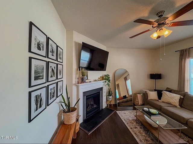 living room with ceiling fan, dark wood-type flooring, and a textured ceiling