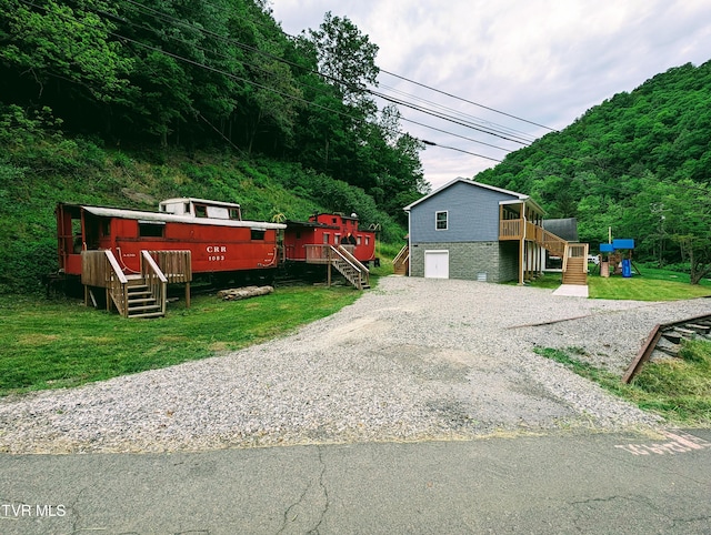 view of front facade with a wooden deck, a garage, and a front yard