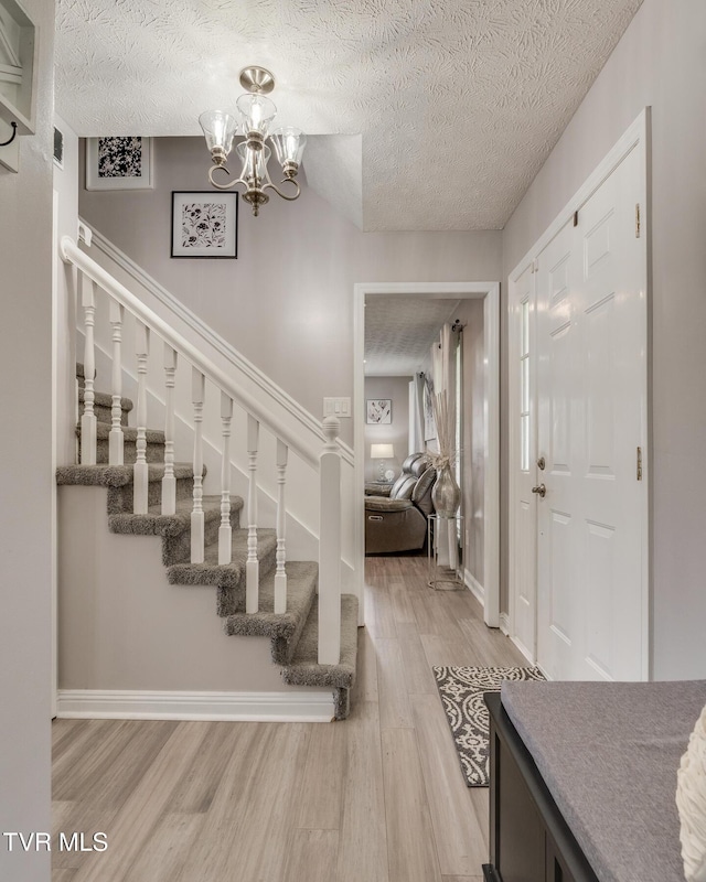 foyer entrance with hardwood / wood-style flooring, a chandelier, and a textured ceiling