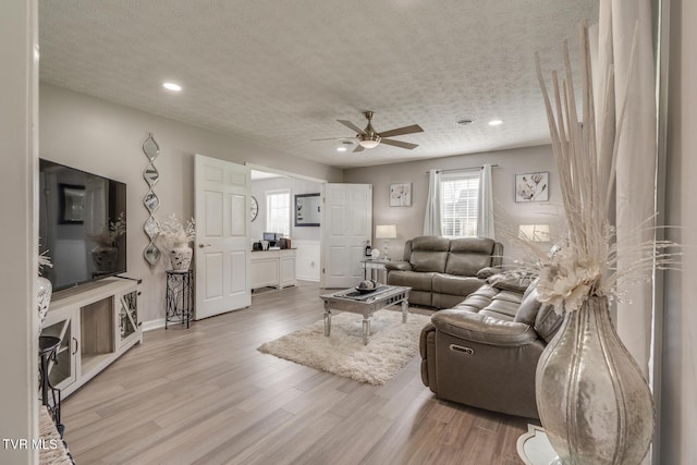 living room featuring wood-type flooring, ceiling fan, and a textured ceiling