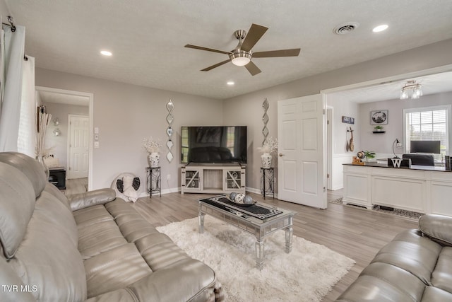 living room with ceiling fan, a textured ceiling, and light hardwood / wood-style floors