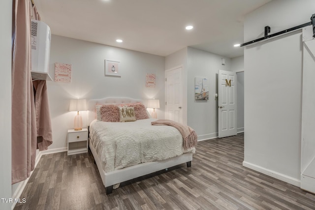 bedroom featuring hardwood / wood-style flooring and a barn door