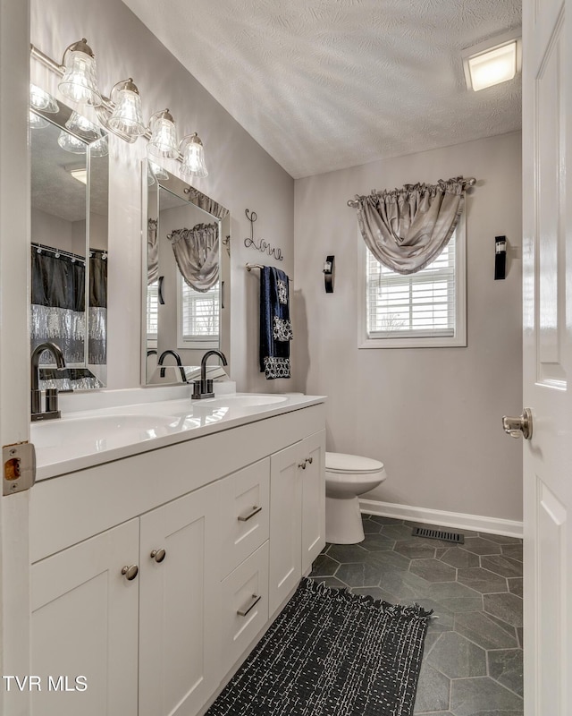 bathroom with vanity, plenty of natural light, toilet, and a textured ceiling