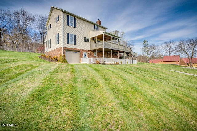 rear view of property with a garage, a balcony, and a yard