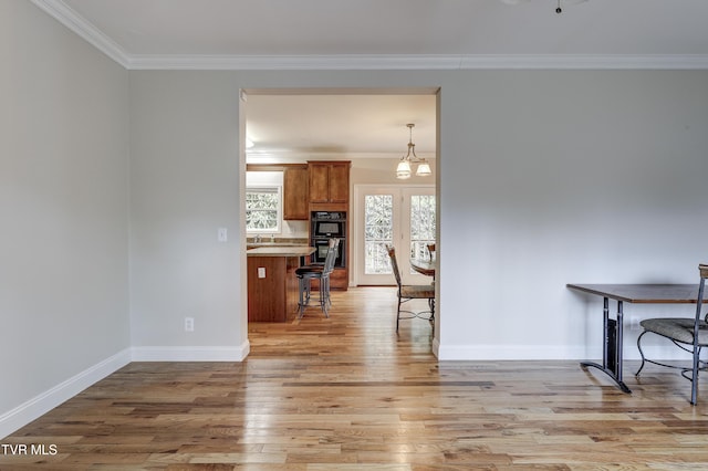 interior space featuring ornamental molding, an inviting chandelier, and light hardwood / wood-style flooring