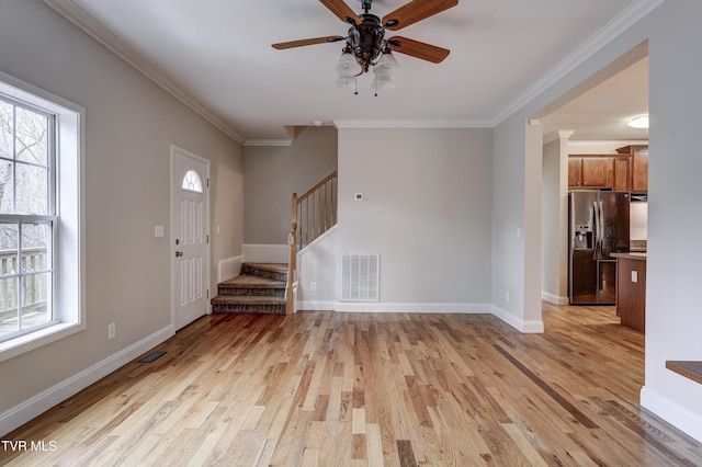 entrance foyer with ornamental molding, light hardwood / wood-style floors, and a wealth of natural light