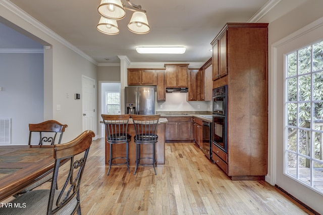 kitchen with a kitchen island, pendant lighting, black dishwasher, stainless steel fridge with ice dispenser, and light hardwood / wood-style flooring