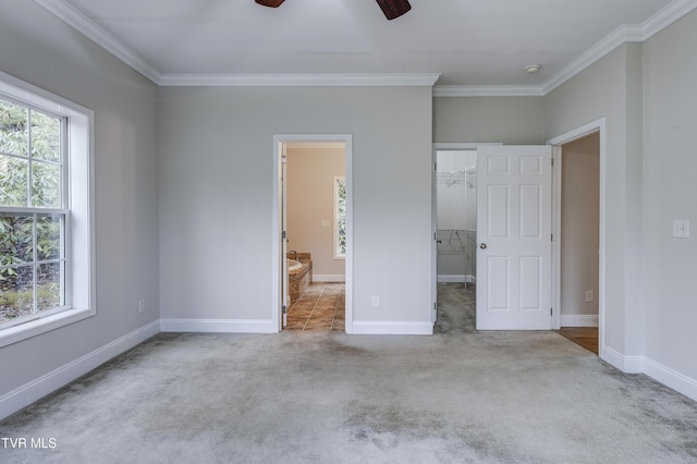 unfurnished bedroom featuring ornamental molding, a spacious closet, light carpet, and ensuite bathroom