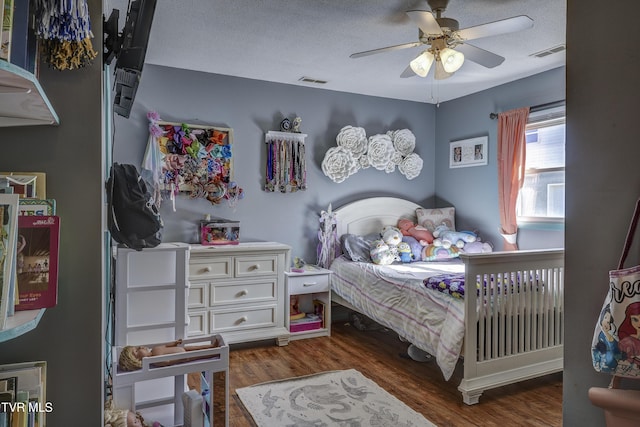 bedroom featuring ceiling fan, dark hardwood / wood-style floors, and a textured ceiling