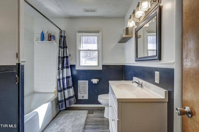 full bathroom featuring heating unit, wood-type flooring, vanity, toilet, and shower / bath combo with shower curtain