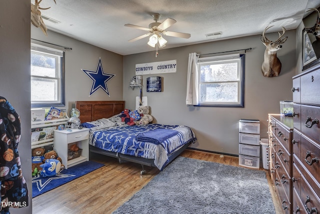 bedroom featuring multiple windows, hardwood / wood-style floors, and a textured ceiling