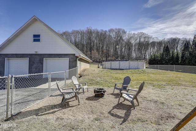 view of yard featuring a garage, a fenced in pool, and a fire pit