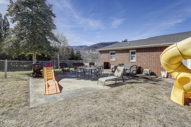 view of patio featuring a playground and a mountain view