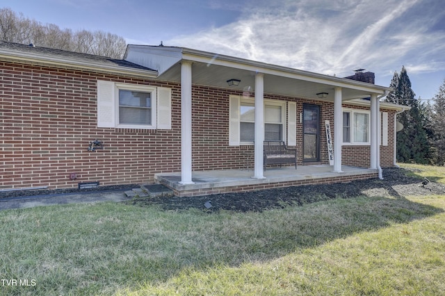 view of side of property with a yard and covered porch