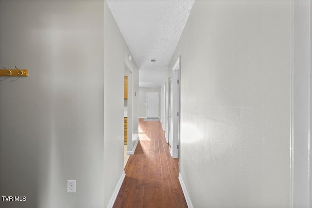 hall with wood-type flooring and a textured ceiling