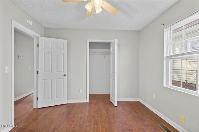 unfurnished bedroom with ceiling fan, dark hardwood / wood-style floors, a textured ceiling, and a closet