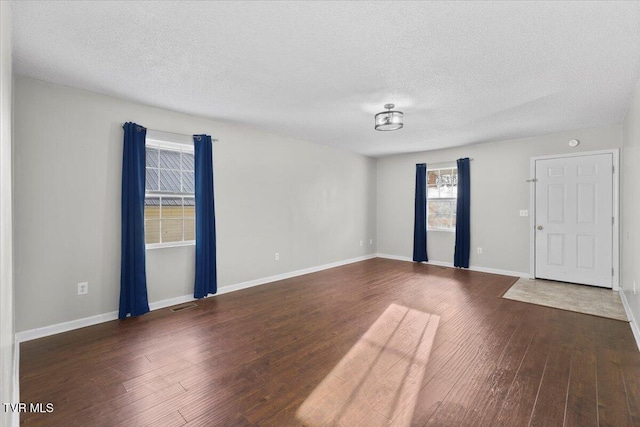 spare room with dark wood-type flooring and a textured ceiling