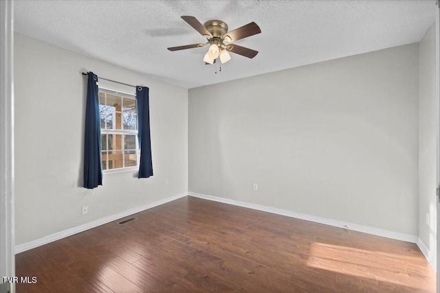 empty room featuring ceiling fan, dark wood-type flooring, and a textured ceiling