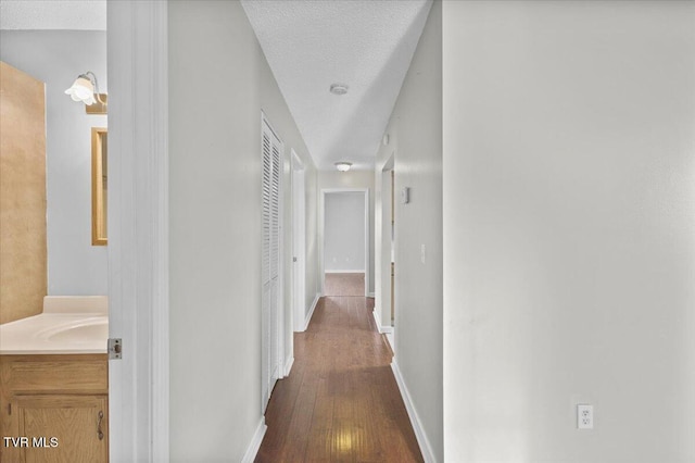 hallway featuring dark hardwood / wood-style flooring, sink, and a textured ceiling