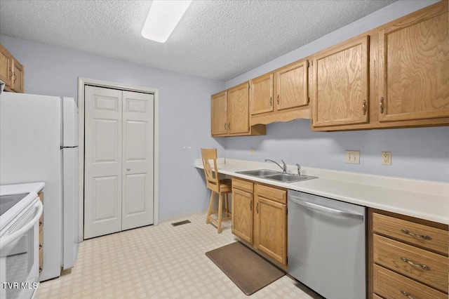 kitchen with white appliances, light brown cabinetry, sink, and a textured ceiling